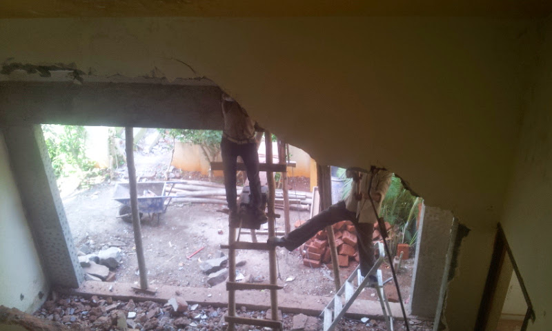 Interior demolition and renovation in progress, with two workers cutting into an archway