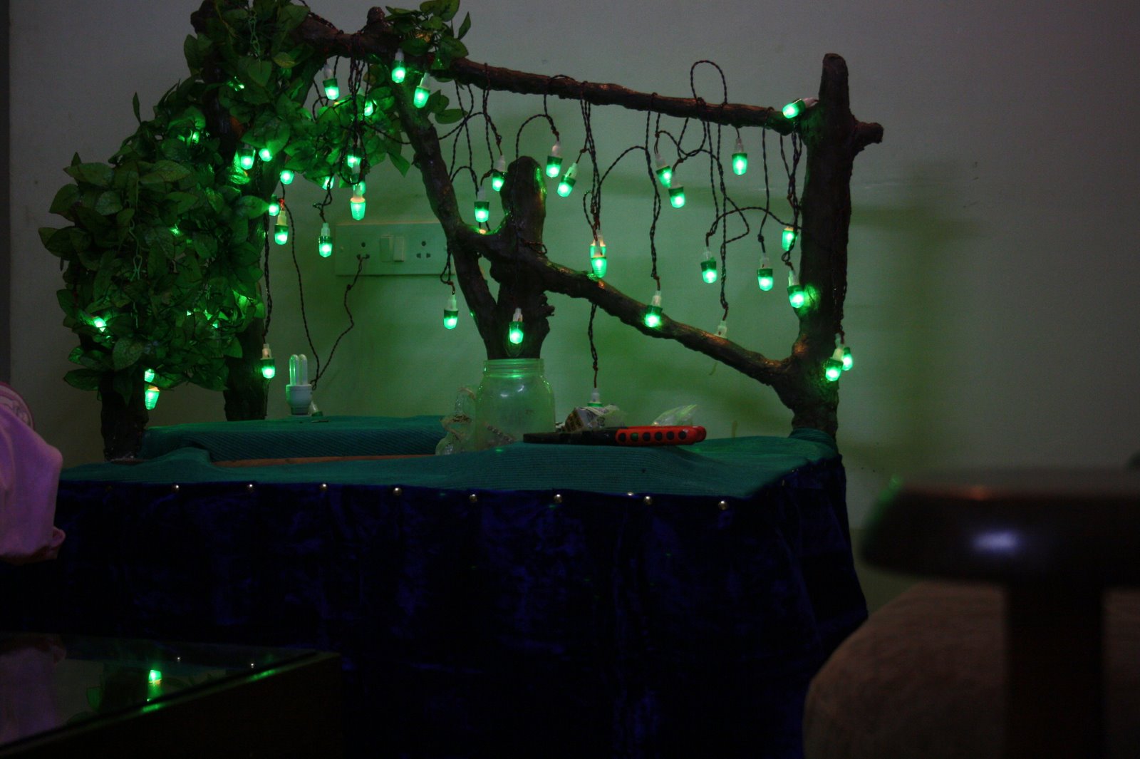 Branch structure being decorated with tiny green lanterns and leaves during setup