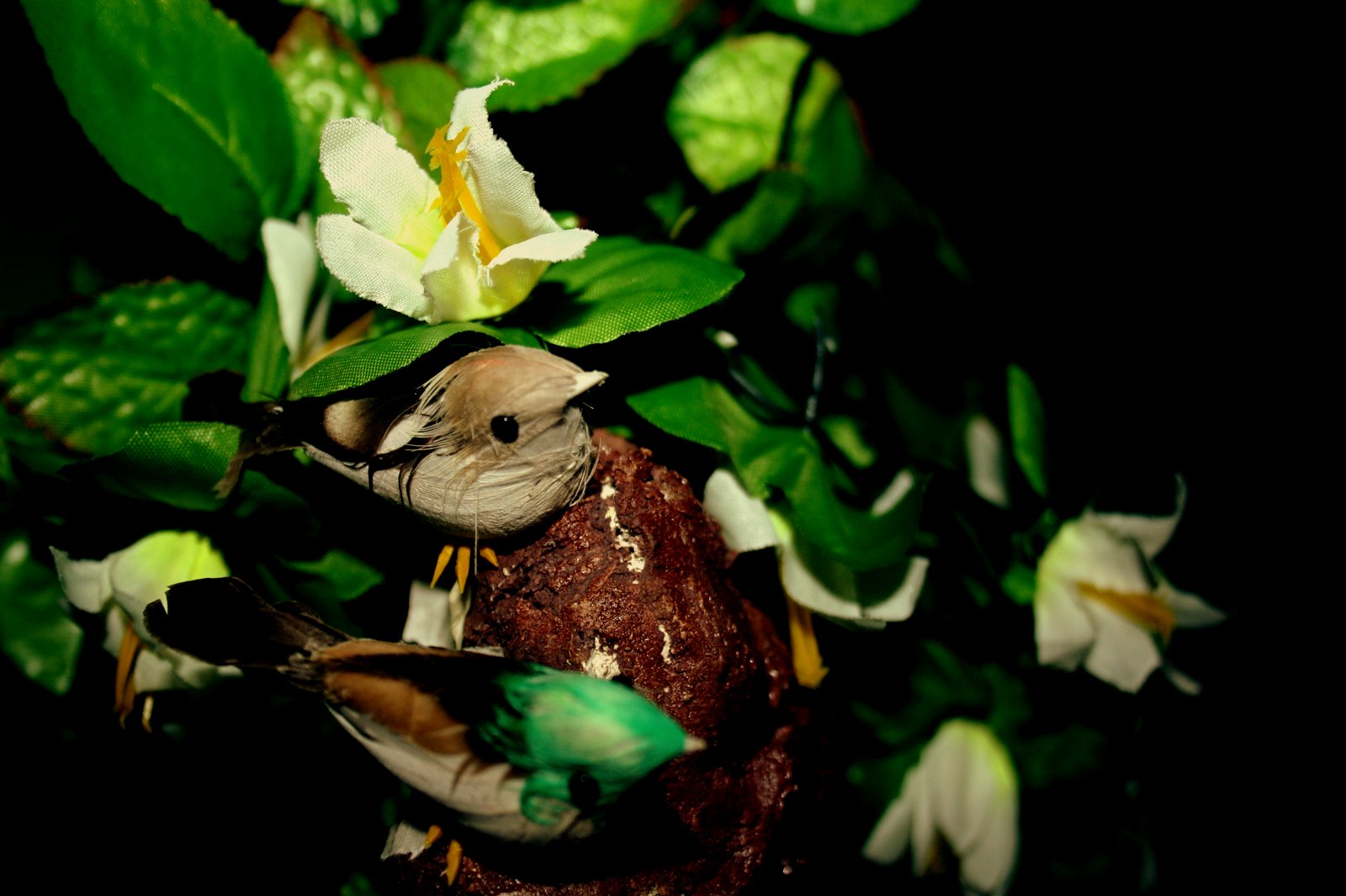 Detail of a small bird tucked amongst white and yellow silk flowers