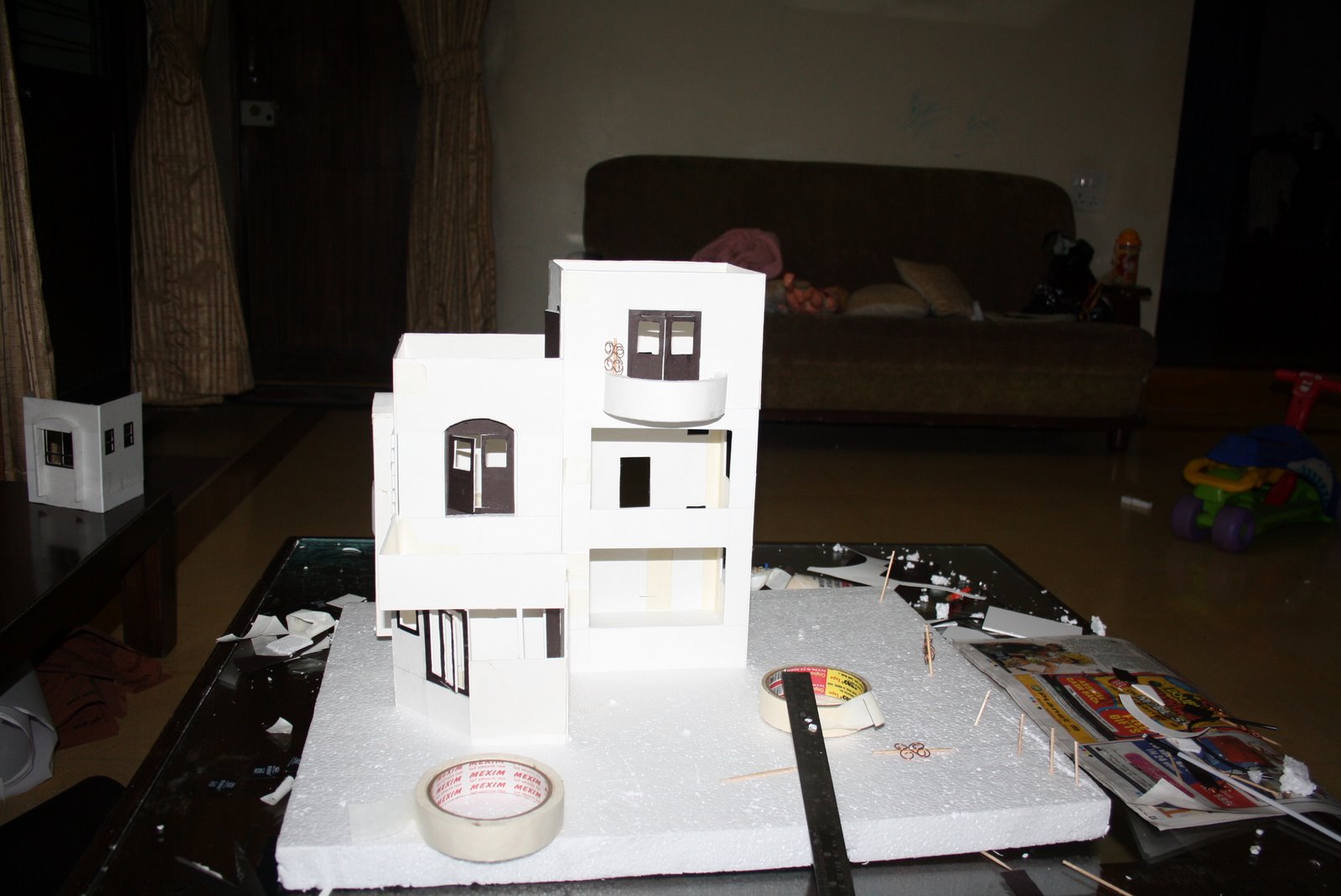 A white paper architectural model of a two-storey house on a foam-board base