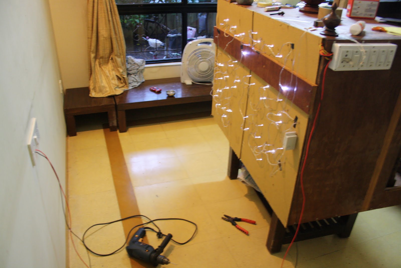 LED string lights being installed on a wooden panel, tools scattered on the floor