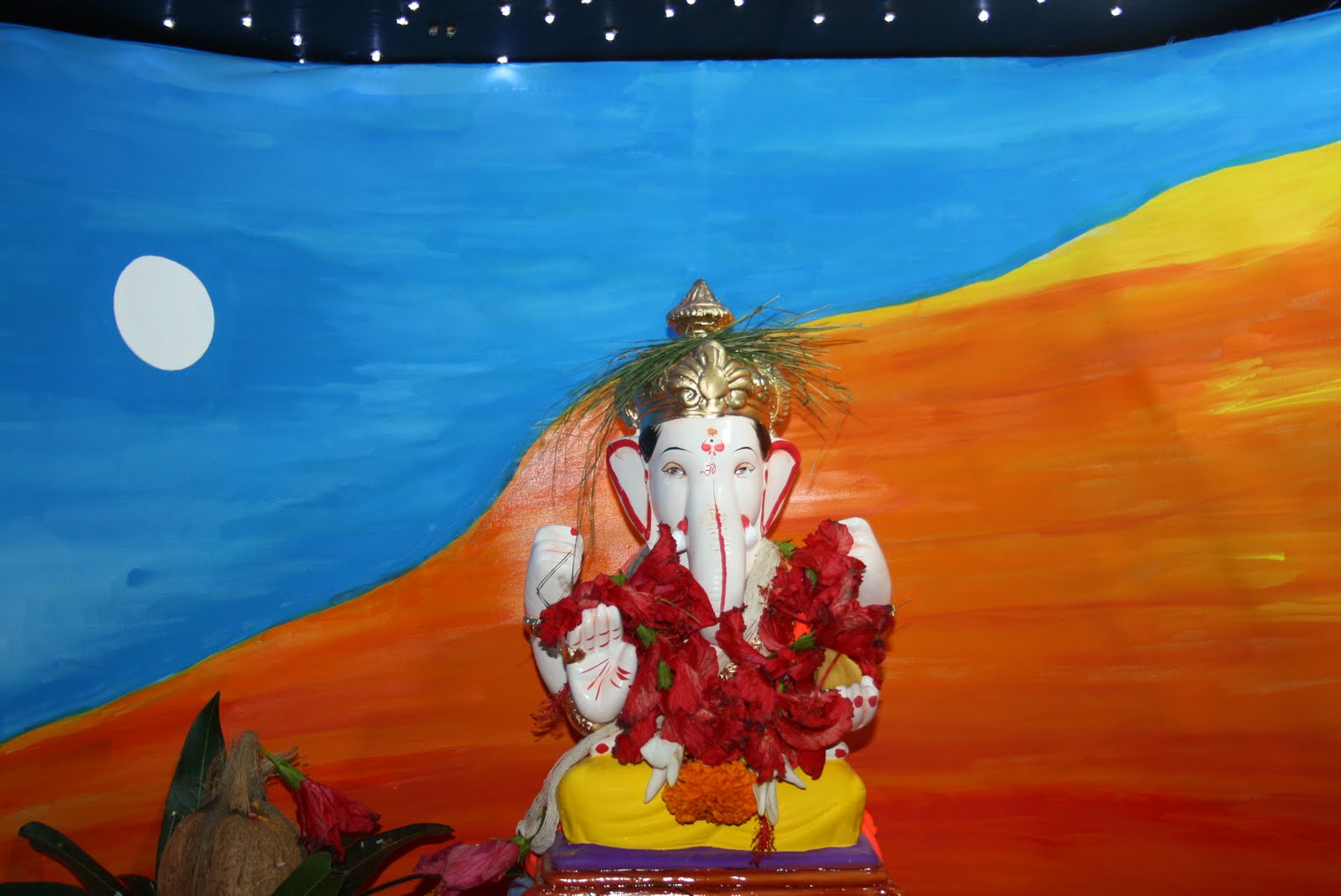 Ganpati with a hand-painted sunset moon backdrop, deep blue sky above orange dunes