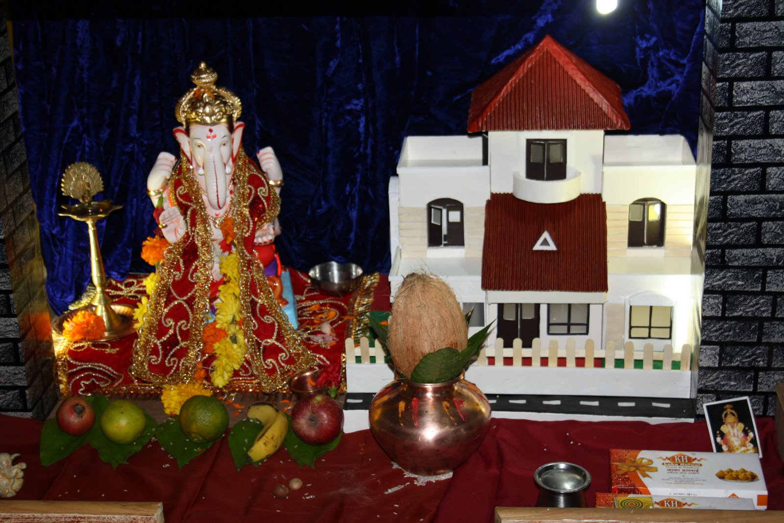Ganpati installation featuring a hand-built house model as a centrepiece, with offerings