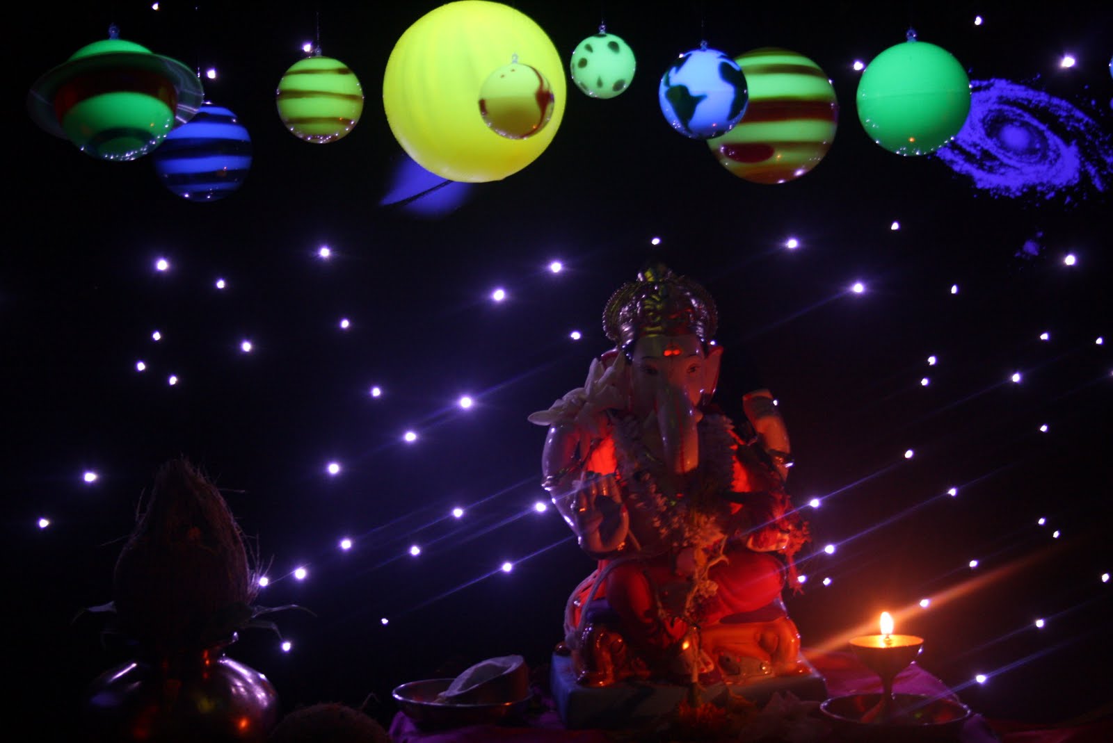 Ganpati installation with hanging planets and stars against a cosmic backdrop