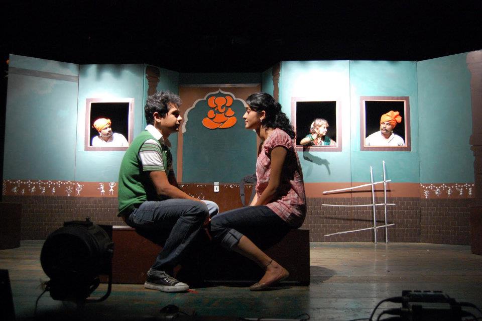 A scene from the play: couple seated, forefathers framed in windows