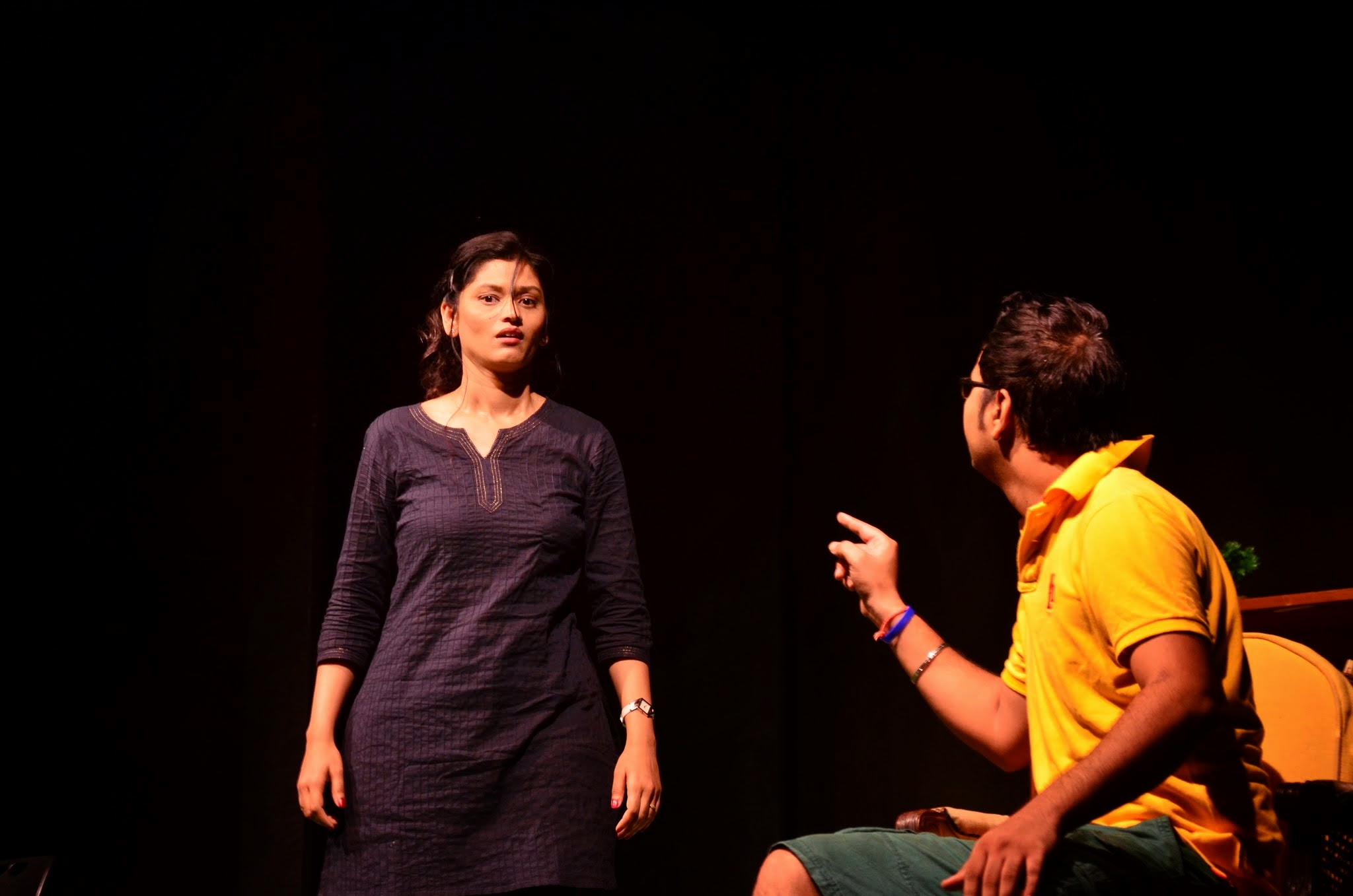 A couple onstage, hands stretched toward each other across an unseen barrier